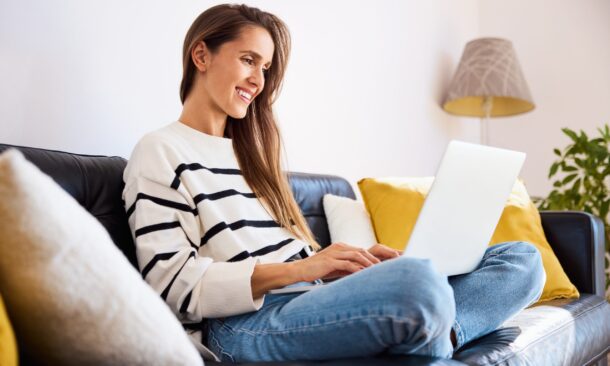 Relaxed,Woman,Working,On,Laptop,Sitting,On,Sofa,At,Home